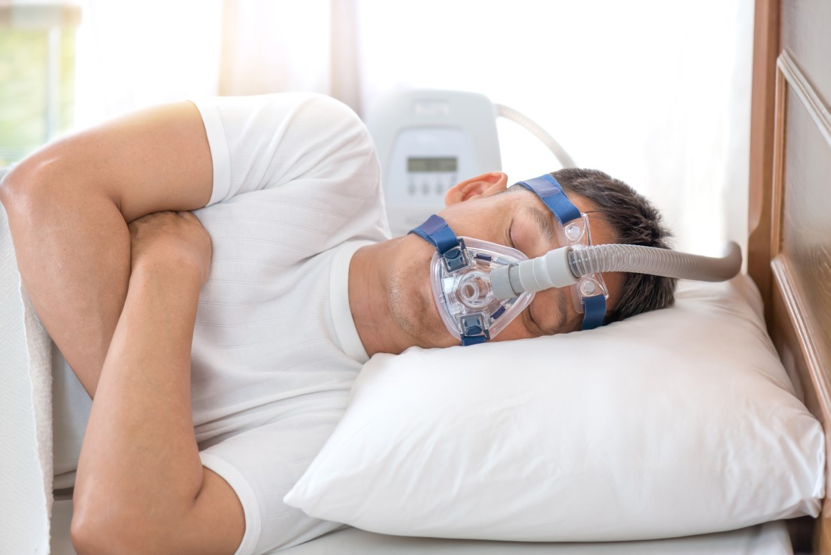 CPAP-Maske auf dem Gesicht eines Mannes mit Schlafapnoe