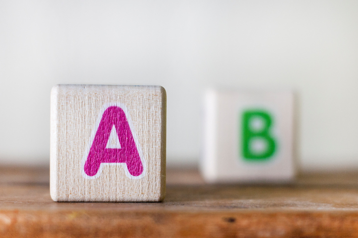 Holzwürfel mit rosa Buchstaben A und grünem B