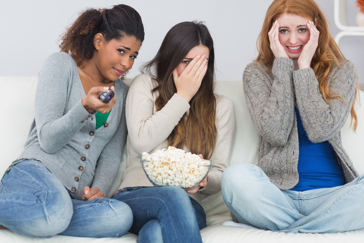 Drei Mädchen haben Angst, schauen sich einen Gruselfilm an, Popcorn in einer Schüssel