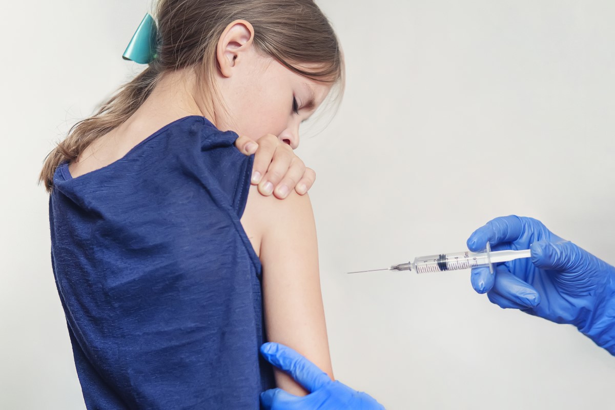 Impfung eines Kindes - eines Mädchens - der Arzt injiziert einen Impfstoff in die Schulter.