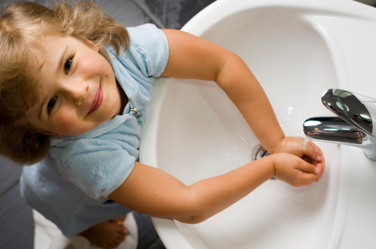 Ein kleines Mädchen wäscht sich die Hände mit sauberem Wasser aus dem Waschbecken