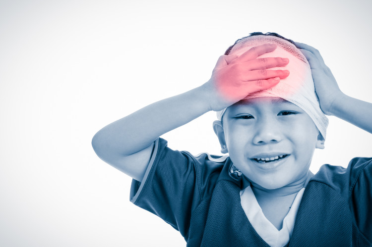 ein Kind hält seinen Kopf nach einem Unfall mit einem Verband