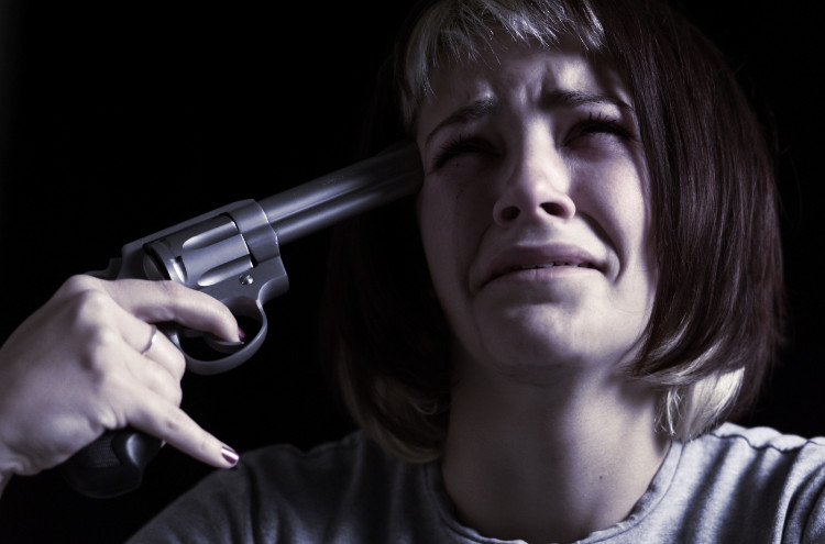eine weinende Frau hält sich eine Pistole an den Kopf