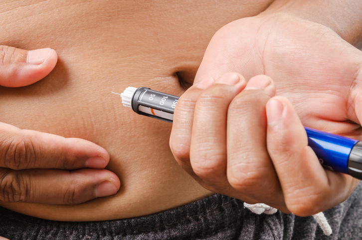 Injektion von Insulin mit einem Insulin-Pen unter die Haut des Unterleibs