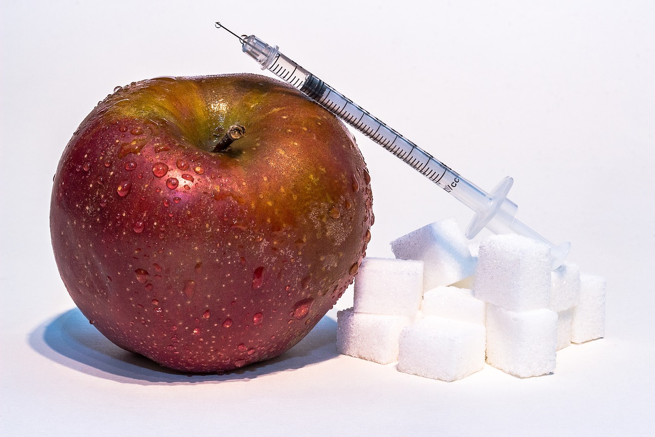 roter Apfel, Zuckerwürfel und Insulinspritze