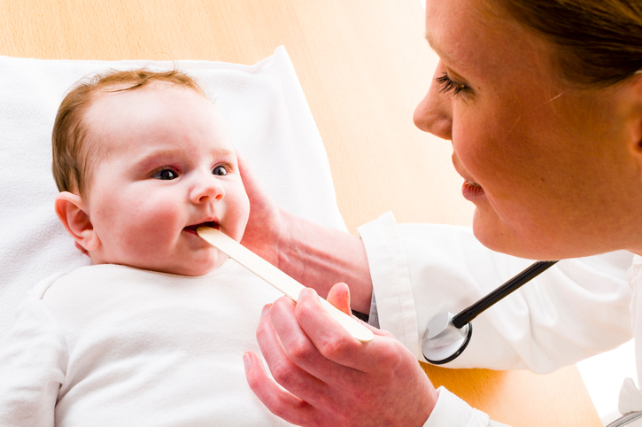 Baby mit offenem Mund, Mutter schaut ihm mit einem Hammer in den Rachen