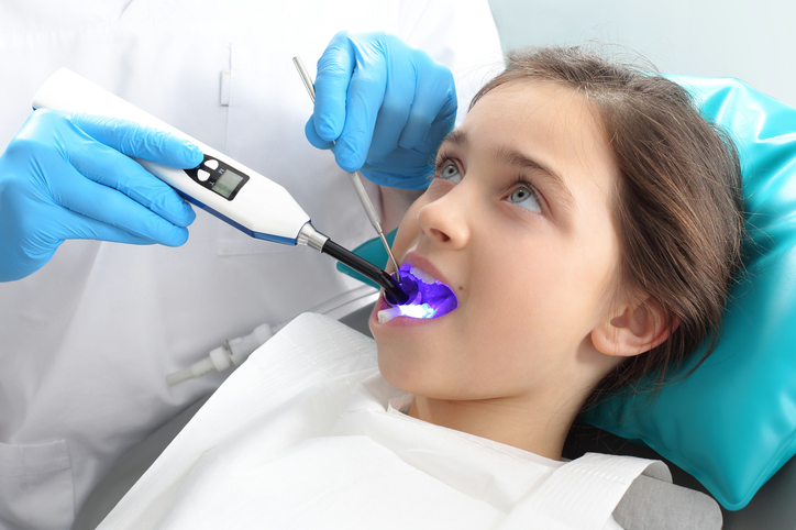 Ein Mädchen auf dem Zahnarztstuhl, das vom Zahnarzt behandelt wird