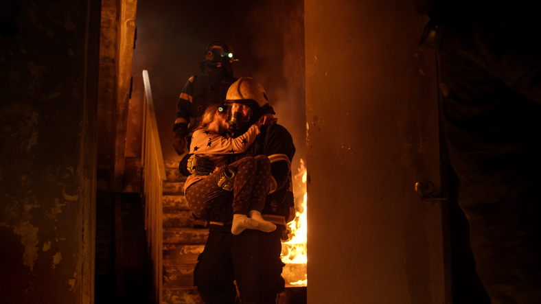 Feuer im Haus, Feuerwehrleute tragen das Kind in ihren Armen hinaus