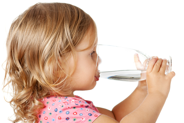 Ein kleines Mädchen trinkt sauberes Wasser aus einem Glas