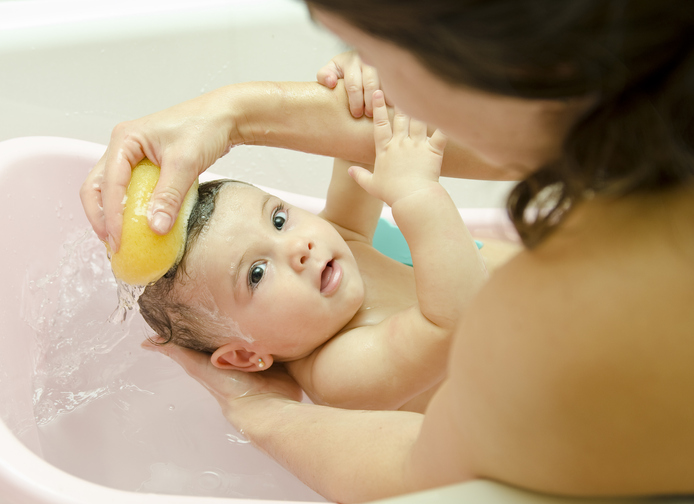 Mutter wäscht ihr Baby in einem Schwammbad