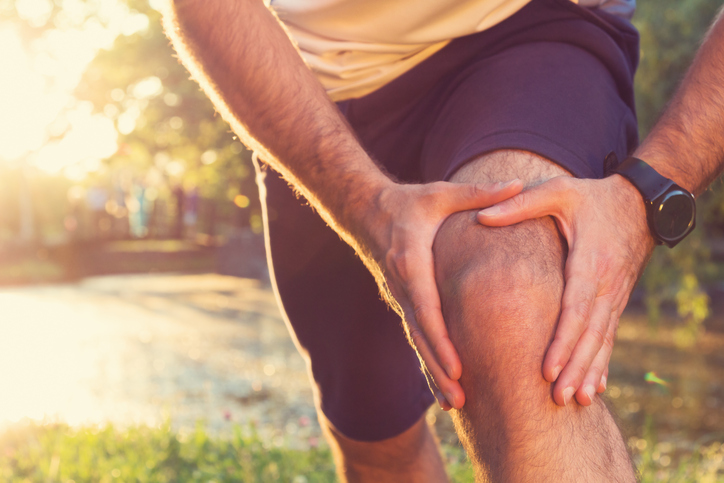 männlicher Sportler, der sein schmerzendes Knie hält