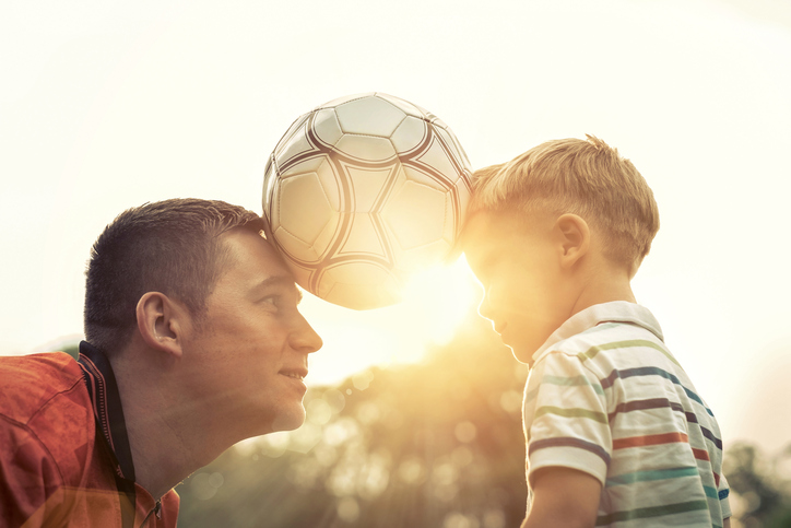 Vater und Sohn halten den Ball zwischen sich.