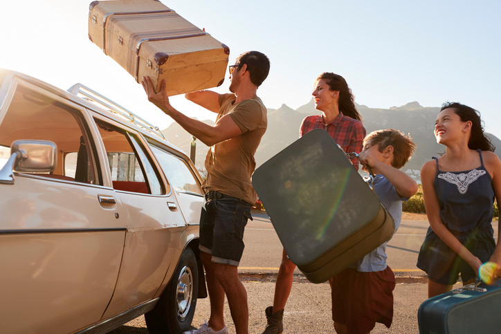 Familie beim Kofferpacken im Auto vor einem Urlaub