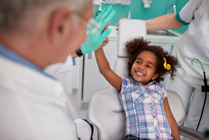 das lachende Mädchen auf dem Zahnarztstuhl mit dem Zahnarzt.