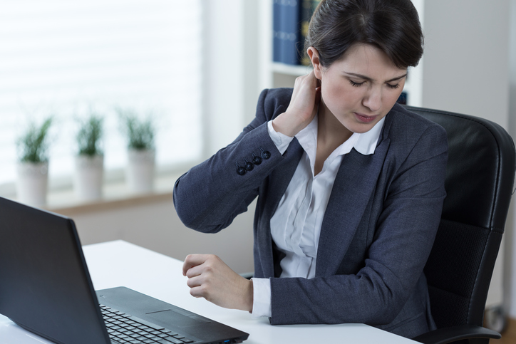 Eine Frau hat Schmerzen in der Halswirbelsäule aufgrund längerer Arbeit am Computer und längerem Sitzen