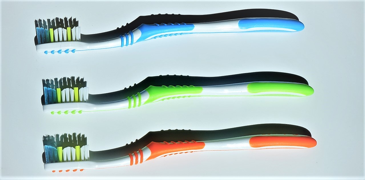 Zahnbürsten, Farbvarianten, dreiteilig, oben blau, in der Mitte grün, unten orange, farbige Borsten am Zahnbürstenkopf, blau, grün und weiß