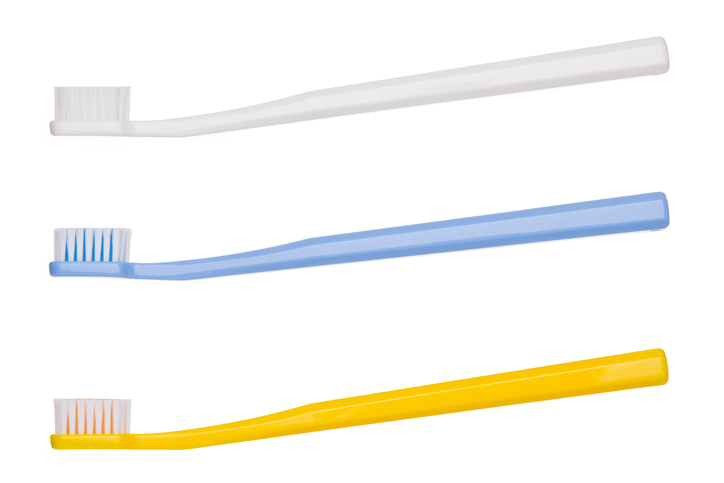 Drei geeignete Zahnbürsten, oben weiß, in der Mitte blau und unten gelb