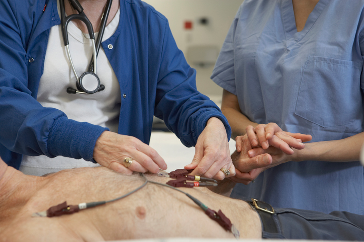 EKG-Untersuchung des Mannes, Elektroden auf seiner Brust, zwei Ärzte untersuchen ihn
