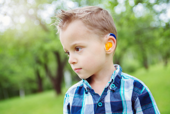 Ein Junge mit farbigen Hörgeräten hat einen Hörverlust.