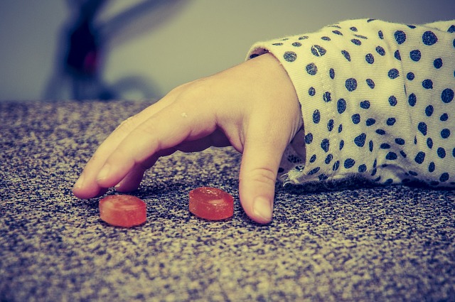 Die Hand eines Kindes, zwei rote Bonbons, schlechte Essgewohnheiten