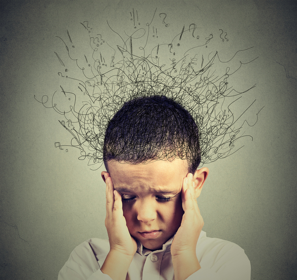 Das Kind hat eine ADHS-Stimmungsstörung, hält den Kopf mit den Händen an den Schläfen, chaotische Gedanken in seinem Kopf, ein Wirrwarr von Fragen und Gedanken, kann sich nicht konzentrieren
