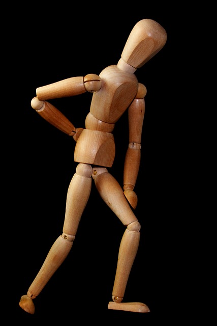 Ein Holzmodell eines Mänchens, das auf den Schmerz im Kreuzbereich hinweist