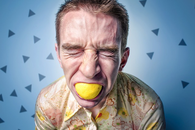 der Mann mit der Zitrone im Mund hat einen sauren Gesichtsausdruck, möglicherweise eine allergische Reaktion auf Zitrusfrüchte