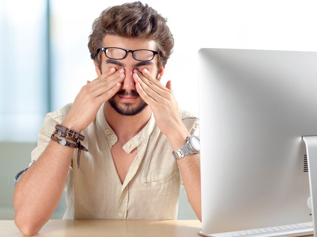 Mann behält seine wunden Augen, hat trockenes Auge Syndrom für die Arbeit an einem Computer für lange Zeiträume