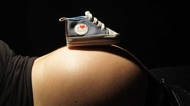 eine schwangere Frau liegt mit einem Schuh auf dem Bauch